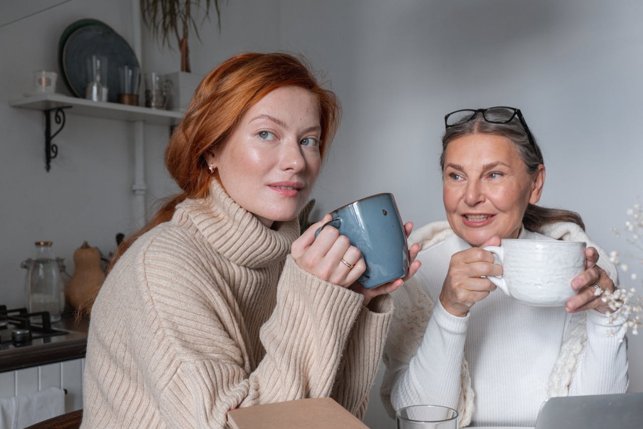 Two women holding mugs in a kitchen setting